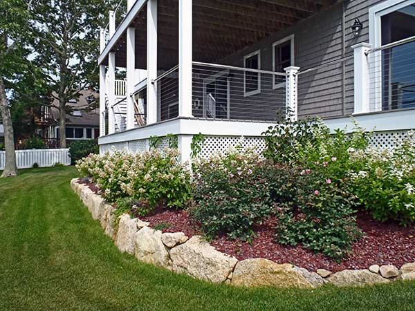A Cape Cod home landscaped with raised plant beds that flow
around this home's foundation.