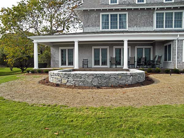 Cape Cod waterfront home with a curved rock patio space. A great example of seaside landscape design and construction.
